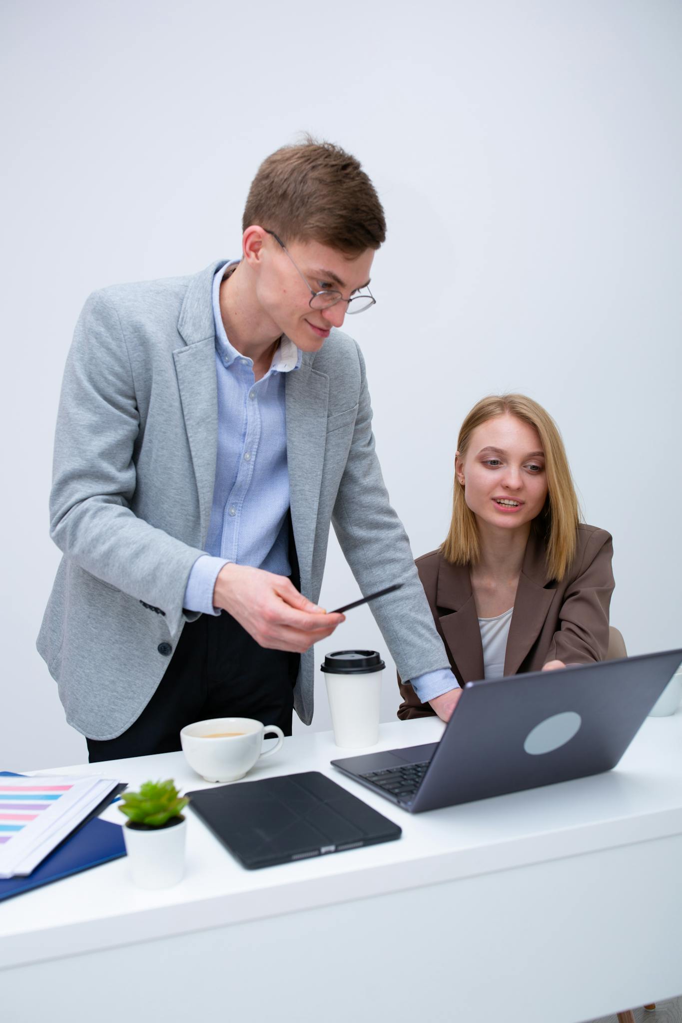 Two business professionals collaborating at a desk with a laptop, engaged in discussion.